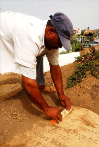 Cleaning dirt off Hebrew tombstone of Abraham Benros